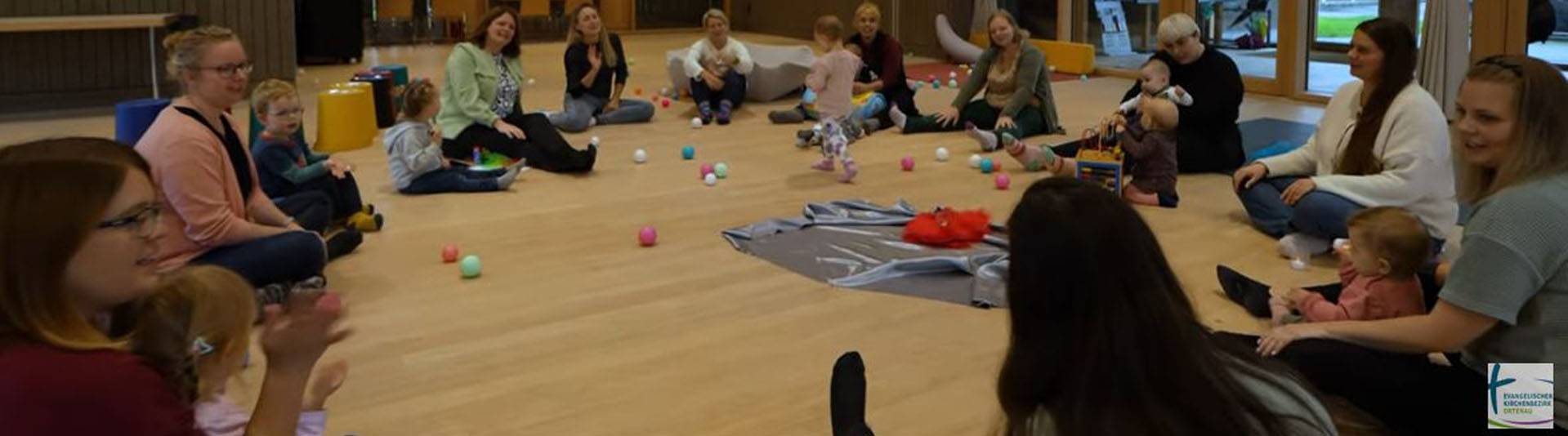 Quelle: Family Light Ortenau Eine Gruppe von Müttern sitz mit ihren Kindern im Kreis auf dem Boden, dazwischen liegt Spielzeug