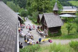 Quelle: Pfarrer Hans-Michael Uhl Blich von oben auf eine Gruppe im freiensitzend zwischen den Häuseren im Freilichtmuseeum Vogtbauernhöfe